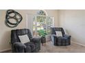 Comfortable living room featuring two plush reclining chairs and a large arched window with natural light at 3042 Gianna Way, Land O Lakes, FL 34638
