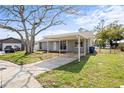Quaint single-story home with a carport and a driveway surrounded by green grass at 3209 Kismet Ct, New Port Richey, FL 34655
