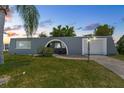 Charming gray home featuring an arched entryway, lush landscaping, and well-maintained green lawn at 3346 Rock Valley Dr, Holiday, FL 34691