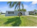 Inviting gray home featuring an arched entryway, attached garage, and well-maintained green lawn at 3346 Rock Valley Dr, Holiday, FL 34691