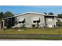 Attractive exterior of home features a well-kept lawn, gray siding, and awning covered windows at 36312 Toranado Way, Zephyrhills, FL 33541