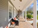 Comfortable front porch featuring brick flooring, cozy seating, and classic white columns at 3733 Wiregrass Rd, New Port Richey, FL 34655