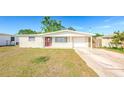 Charming single-story home featuring a red front door and an extended driveway leading to the garage at 4938 Fruitwood Loop, Holiday, FL 34690