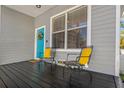 Cozy front porch featuring seating, a vibrant turquoise door, and neutral-toned siding at 513 Meres Blvd, Tarpon Springs, FL 34689