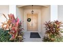 Inviting front entry with double doors, decorative wreath, and colorful tropical plants at 5492 Legend Hills Ln, Spring Hill, FL 34609
