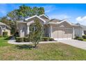 Charming home featuring manicured landscaping, neutral stucco, and attached two-car garage at 5492 Legend Hills Ln, Spring Hill, FL 34609