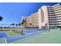 Low-angle of tennis courts and the condo building, complete with ocean views and palm trees at 5915 Sea Ranch Dr # 211, Hudson, FL 34667