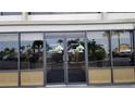 Building entrance featuring double glass doors with decorative logos and views of the parking area at 6035 Sea Ranch Dr # 411, Hudson, FL 34667