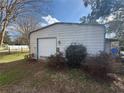 Exterior view of the property's shed, featuring a roll-up door, adjacent to some shrubbery at 6361 Boxwood St, Brooksville, FL 34602