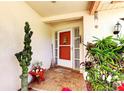 Welcoming front entry with a tiled porch, decorative plants, and a charming, colorful front door at 9925 Whitworth Ct, New Port Richey, FL 34655