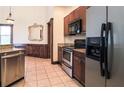 Modern kitchen with stainless steel appliances, dark wood cabinets, and tile flooring at 10056 Lebanon Dr, Port Charlotte, FL 33981