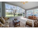 Bright sunroom with large windows offering scenic views, comfortable seating, and tiled floors at 11545 Weaver Park Ct, Trinity, FL 34655