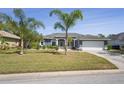 Beautiful single-story home with a well-kept lawn, palm trees, and a two-car garage at 12446 Quail Ridge Dr, Spring Hill, FL 34610