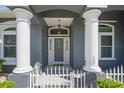 Elegant front entrance featuring decorative glass door flanked by white columns and picket fence at 12446 Quail Ridge Dr, Spring Hill, FL 34610