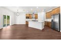 Open-concept kitchen with island, stainless steel appliances, wood cabinets, and hardwood floors at 16043 Penn State Rd, Weeki Wachee, FL 34614