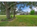 Landscaped front yard with mature trees that frame the charming exterior of this home at 16386 Heron Hills Dr, Spring Hill, FL 34610