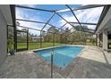 Inviting screened-in pool area featuring a refreshing pool and brick patio, perfect for outdoor relaxation at 16386 Heron Hills Dr, Spring Hill, FL 34610