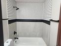 A remodeled bathroom with black and white tiled walls, a white tub, and dark fixtures at 4601 N 37Th St, Tampa, FL 33610