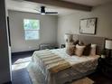 Bright main bedroom with hardwood floors, a ceiling fan, and plush bedding at 4601 N 37Th St, Tampa, FL 33610