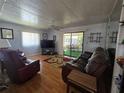 Inviting living room with wood-look flooring, comfortable seating, and sliding doors to the lanai at 5211 Wisteria Cir, New Port Richey, FL 34653