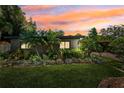 Charming single-story home with manicured landscaping, lush green lawn, and a beautiful sunset at 6433 Murray Hill Dr, Tampa, FL 33615
