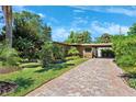 Charming single-story home with a brick driveway, lush landscaping, and an inviting carport at 6433 Murray Hill Dr, Tampa, FL 33615