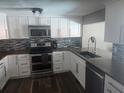 Modern kitchen with white cabinetry, stainless steel appliances, stylish backsplash, and beautiful wood-look flooring at 8501 Hunting Saddle Dr, Hudson, FL 34667