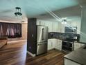 Updated kitchen with stainless steel appliances, white cabinets, and wood-look flooring open to the living area at 8501 Hunting Saddle Dr, Hudson, FL 34667