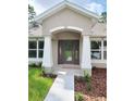 Inviting front door with decorative glass, framed by white columns and manicured landscaping at 11192 Kodiak Wren Rd, Weeki Wachee, FL 34614