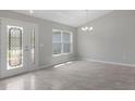 Spacious room featuring elegant gray tiling, a chandelier, a window, and glass paneled front door at 11192 Kodiak Wren Rd, Weeki Wachee, FL 34614