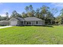 Inviting single-story home with a lush green lawn and long concrete driveway leading to an attached two-car garage at 11388 Paramount Ave, Weeki Wachee, FL 34614