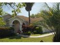 Inviting single-story home with a palm tree in front and a winding walkway leading to the entrance at 11480 Emerald Ridge Ct, Spring Hill, FL 34609
