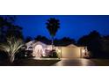 Charming single-story home with beautiful landscaping, a palm tree and inviting curb appeal at twilight at 11480 Emerald Ridge Ct, Spring Hill, FL 34609