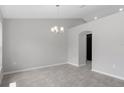 Open dining room with neutral walls, tile flooring, modern chandelier, and arched doorway at 13066 Nusser Ave, Weeki Wachee, FL 34614