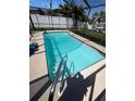 Inviting in-ground pool with a safety ladder, enclosed by a screen, and surrounded by a well-kept yard at 13630 Lagoon Dr, Hudson, FL 34667