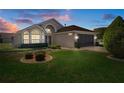 Charming single-story home with well-maintained landscaping and an attached two-car garage at dusk at 13643 Pimberton Dr, Hudson, FL 34669