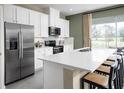 Modern kitchen features stainless steel appliances, white cabinets, a center island with seating, and a backyard view at 2229 Nancy Lee Dr, Lutz, FL 33558