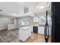 Bright kitchen featuring white cabinets, an island, and modern black appliances at 2608 W Fletcher Ave, Tampa, FL 33618