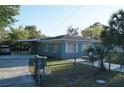 A view of the property showcasing its fenced yard, carport, and blue painted exterior at 3421 E Powhatan Ave, Tampa, FL 33610