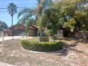 A single-story home with a well-manicured yard, circular landscaping, and mature trees at 5005 Kirkwood Ave, Spring Hill, FL 34608