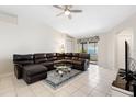 Cozy living room features a comfortable leather sectional, a ceiling fan, and sliding doors to the patio at 11023 Silver Dancer Dr, Riverview, FL 33579