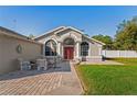 Inviting front entrance features a red double door, arched windows, and a cozy patio seating area at 13045 Marbled Godwit Rd, Weeki Wachee, FL 34614