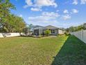 Spacious backyard featuring a screened-in pool area and a large grassy area, surrounded by a white fence at 13619 Bee Tree Ct, Hudson, FL 34669