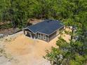 View of the rear of the home showing siding, windows and the roof in the wooded homesite at 18082 Parakeet Rd, Brooksville, FL 34614