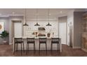 Modern kitchen showcasing a large center island with bar stool seating, pendant lighting, and sleek white cabinetry at 4112 Southern Valley Loop, Brooksville, FL 34601