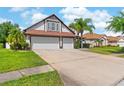 Expansive driveway leading to the two-car garage of this home, with landscaped yard at 5737 Wynstone Ln, Zephyrhills, FL 33541