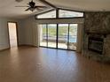 Open floor plan with vaulted ceiling, stone fireplace, and sliding glass doors leading to the balcony at 5956 Seaside Dr, New Port Richey, FL 34652