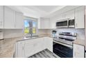Bright kitchen featuring white cabinets, stainless steel appliances, and granite countertops at 8626 White Springs Dr, New Port Richey, FL 34655