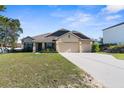 Charming single-story home featuring a three-car garage and a well-manicured front lawn at 12450 Fish Cove Dr, Spring Hill, FL 34609