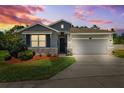 Charming single-Gathering home with a two-car garage, stone accents, lush landscaping, and a well-manicured lawn at dusk at 15793 Midnight Dove Ct, Odessa, FL 33556